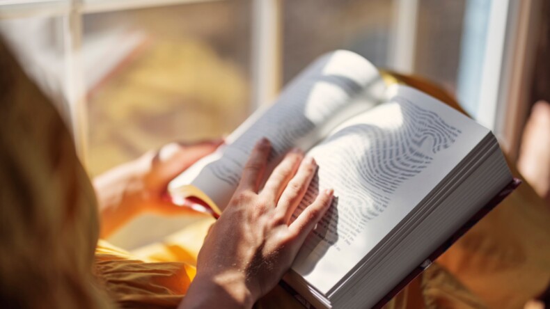 Nainen lukee kirjaa ja teksti näyttää vääristyvän